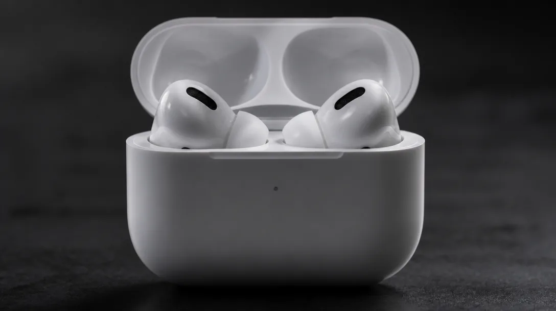 Apple AirPods Pro i laddetui närbild, dramatisk studiomiljö med fokuserat ljus mot mörk bakgrund